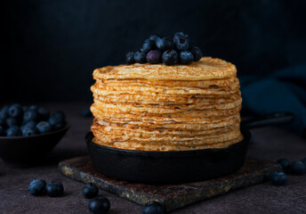 Homemade thin pancakes in a frying pan with blueberries, maslenitsa, selective focus