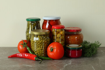 Jars with different pickled food on gray table