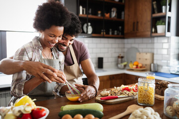 Happy black couple cooking and tasting healthy food in kitchen