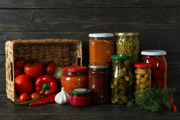 Jars with different canned food on wooden background