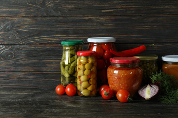 Jars with different canned food on wooden background