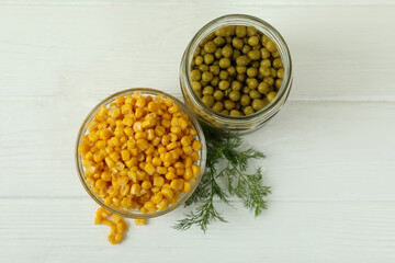 Canned peas and corn on white wooden background