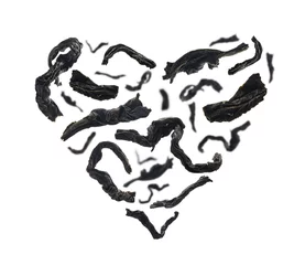 Vitrage gordijnen Thee assortiment Gedroogde zwarte thee close-up in de vorm van een hart op witte achtergrond