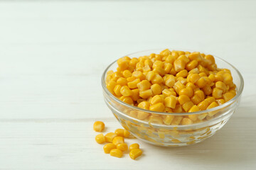 Bowl with canned corn on white wooden background