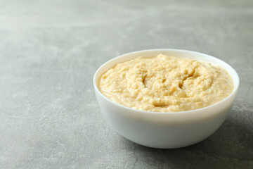 Bowl of fresh hummus on gray background