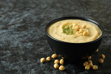 Bowl of fresh hummus on black smokey background