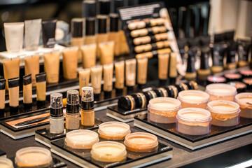 The tonal creams, powder, makeup base and correctors for the skin of the face in jars and tubes are set on the table in the shelves of a beauty salon. Probes different cosmetics.