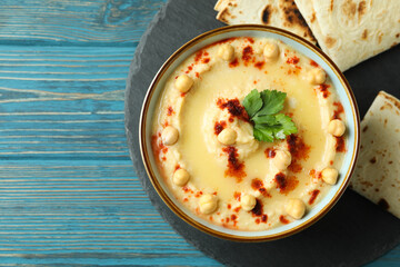Tray with bowl of hummus and pita on wooden background