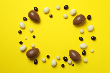 Easter chocolate eggs and candies on yellow background