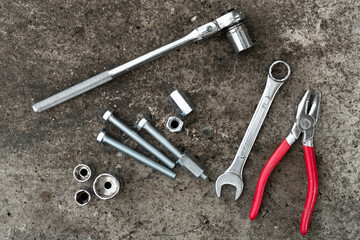 Ratched wrench, plier, bolts and wrenches on concrete background. Equipment. Engineering