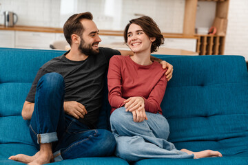 Happy young couple hugging and using remote control while watching TV