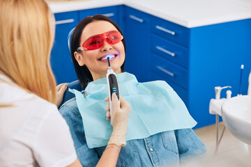 Positive delighted brunette doing teeth whitening procedure