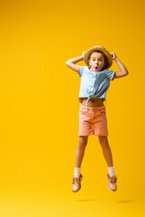 full length of shocked kid in straw hat levitating on yellow