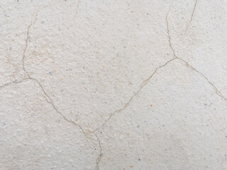 Fototapeta premium stone wall texture. Beige cracked cement with fine gravel surface. Ferruginous cracks on plaster wall. Old stucco wall with marble grains and rusty cracks.