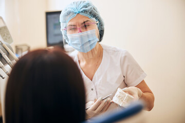 Young attentive stomatologist looking at her patient