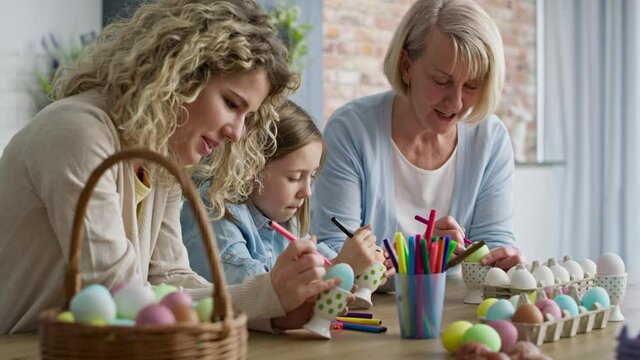 Video of girl with mother and grandma coloring Easter eggs. Shot with RED helium camera in 8K.