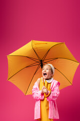 amazed girl in raincoat standing under umbrella on crimson