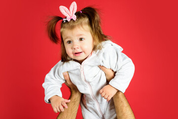 Cute funny baby with bunny ears and pigtails on parent hands.