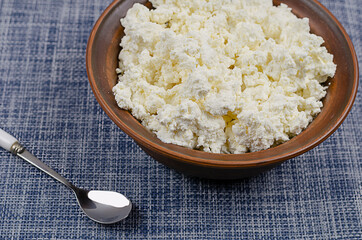 A full bowl of curd and a spoon on a blue and white background.