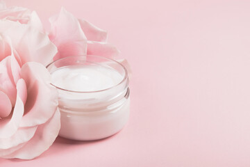 Cosmetic cream with rose essential oil on pink background. Facial or body skincare, beauty...