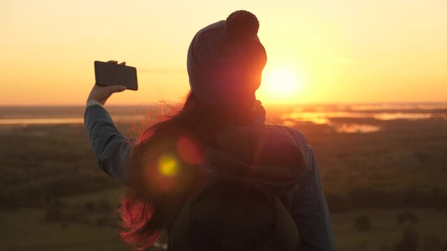 Young girl tourist blogger records a selfie video on top of mountains using smartphone with a beautiful landscape. Girl hiker. Healthy Free woman travels at dawn and photography nature on phone.