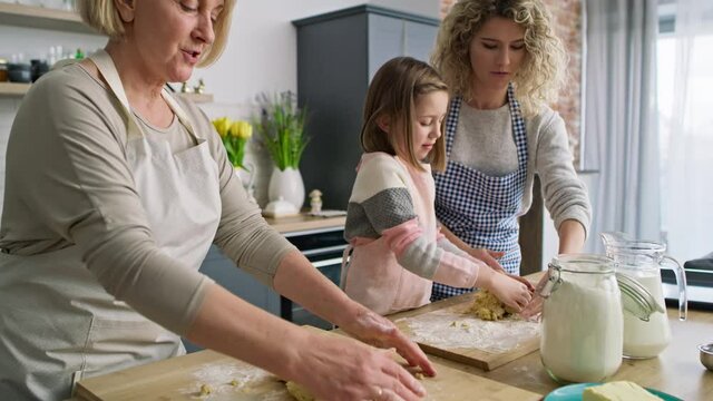 Video of three generations of women kneading dough in kitchen. Shot with RED helium camera in 8K.