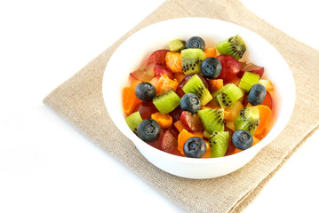 Fresh fruit salad for breakfast in a white bowl on an isolated white background.