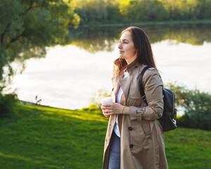 Relaxed beautiful girl on the nature in the rays of the sun. Holding a cup of coffee