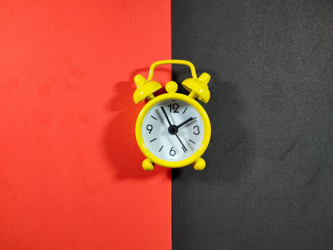 Selective focus.A yellow clock on a red and black background.Shot were noise and film grain.