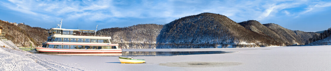 Panorama of the beautiful landscape with snow and excurision ship at the Edersee in winter.