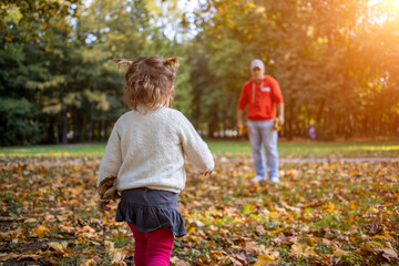 Fototapeta premium little toddler girl plays with father outdoors in autumn park