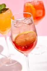 Cocktail garnished in wine glass with lemon slice and ice cube. Sunlight with hard shadow. Closeup view. Fresh, summer drink concept