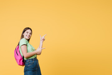 Cheerful teenager pointing with fingers isolated on yellow