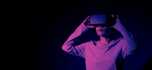 Girl with hands up wearing the VR headset goggles. Asian woman in glasses of virtual reality. The concept of futuristic. Digital VR glasses. Woman getting cyber experience using modern black color VR.