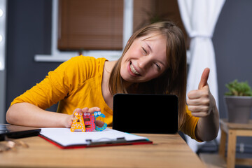 International language online school concept. Smiling woman with like, thumb up showing mock up digital tablet screen on home background. Cool distance learning