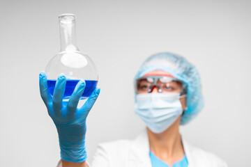 Fototapeta premium Woman scientist holding laboratory flask with chemical liquid, gray background