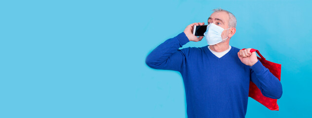 man with surgical mask using mobile phone and bag, online shopping concept in time of pandemic and new normal