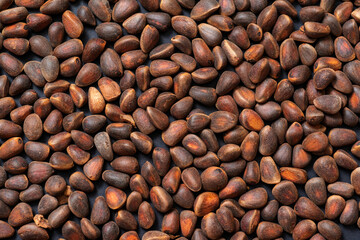Background unpeeled Siberian pine nuts in a shell close-up. 