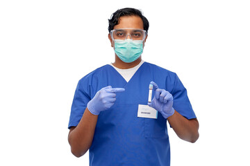 healthcare, coronavirus and medicine concept - indian doctor or male nurse in blue uniform, face mask for protection from virus, goggles and gloves with blood in test tube over white background