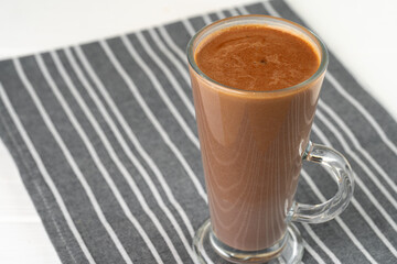 Glass cup of cocoa drink on white wooden table