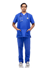 healthcare, profession and medicine concept - indian doctor or male nurse in blue uniform with stethoscope over white background