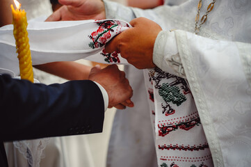 Hands of bride and groom tied Wedding towel, close up. The priest binds the bride's hand towel. Brides at a wedding ceremony in a church