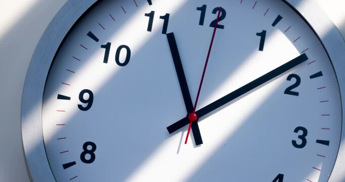 Sun and sky reflecting in the watch during the time passing by. Time lapse on a modern wall clock at noon. Wall clock show the running time. Close up to a wall clock, with running time pointer. 