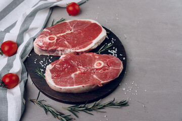 Fototapeta na wymiar Raw rib-eye beef steak on wooden cutting board on gray background