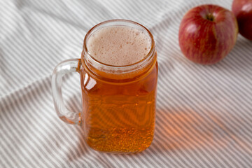 Hard Apple Cider Ale in a Glass Jar Mug on cloth, low angle view. Close-up.
