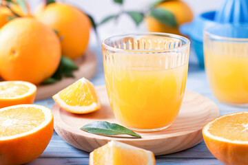 Two glasses of fresh juice, fruit squeezer and ripe fresh oranges on blue wooden table top, fresh orange juice making, top view