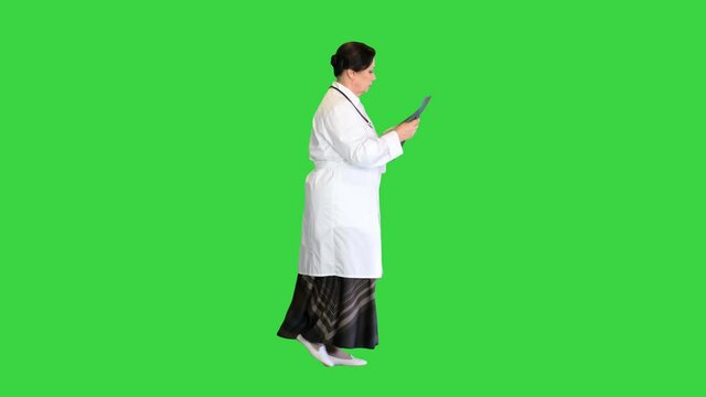 Female doctor examining lungs x-ray while walking on a Green Screen, Chroma Key.