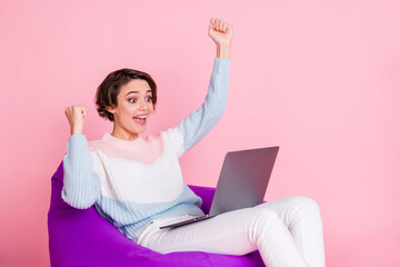 Profile photo of delighted person sitting soft chair look laptop fists up celebrate isolated on...