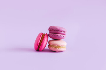 Tasty french macarons on a violet pastel background. Pink and violet macarons.