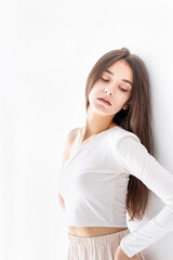 Young sad woman standing alone by the wall looking away